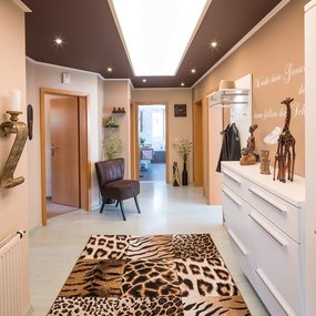 Heller Flur mit afrikanischer Dekoration, Tierfell-Teppich und moderner Einrichtung.