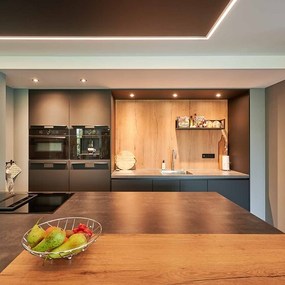 Moderne Designküche mit Kochinsel, Obstschale, Einbaugeräten und stilvoller Beleuchtung.