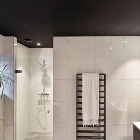 Modernes Badezimmer mit begehbarer Dusche, weißen Fliesen und schwarzem Handtuchheizkörper.